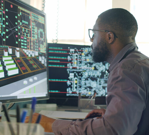 tock image of an Afro-Caribbean male designing electronic circuit boards ( PCBs).
He’s sitting at a desk with a large computer screen displaying a variety of apps