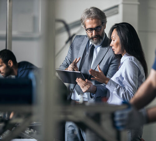 Quality control inspectors working on digital tablet in a production line.