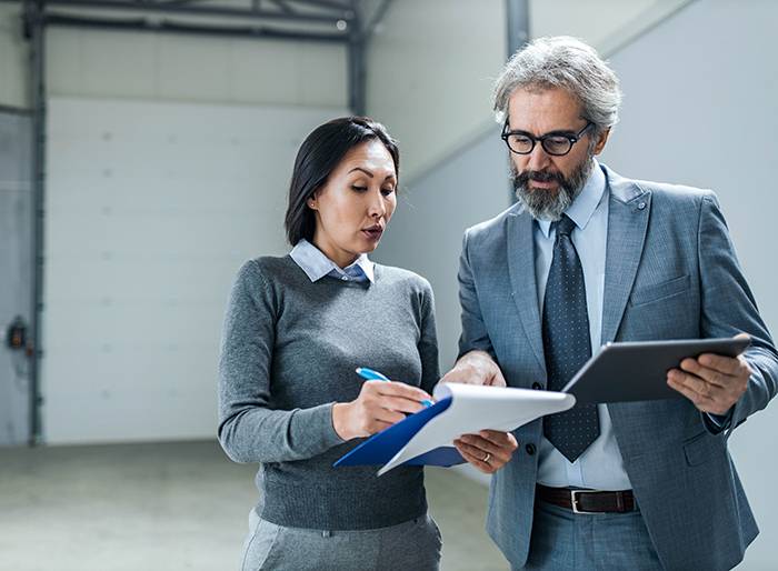 rest-api Asian businesswoman and her male colleague working on reports and touchpad in a factory.