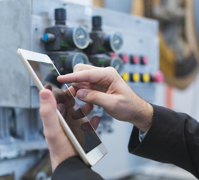 Shop floor lead uses tablet in front of manufacturing machine
