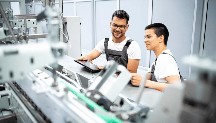 Two manufacturers are adjusting a machine on the shop floor.